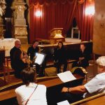 Der G'mischte Sax spielt in der Kirche. Im Vordergrund sitzt Publikum.